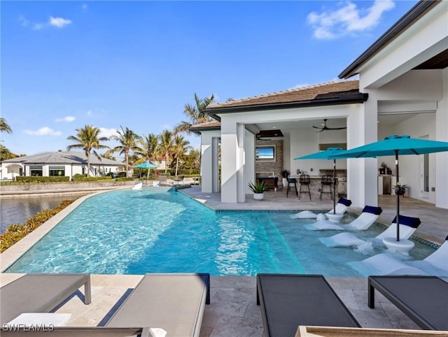 view of swimming pool featuring a bar, ceiling fan, and a patio area