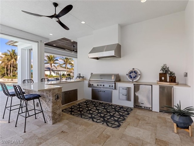 view of patio featuring exterior kitchen, a bar, area for grilling, and ceiling fan