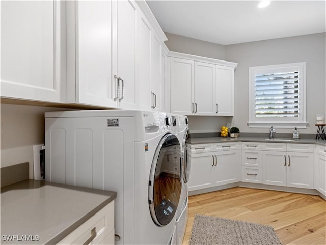 laundry area with independent washer and dryer, cabinets, light hardwood / wood-style flooring, and sink