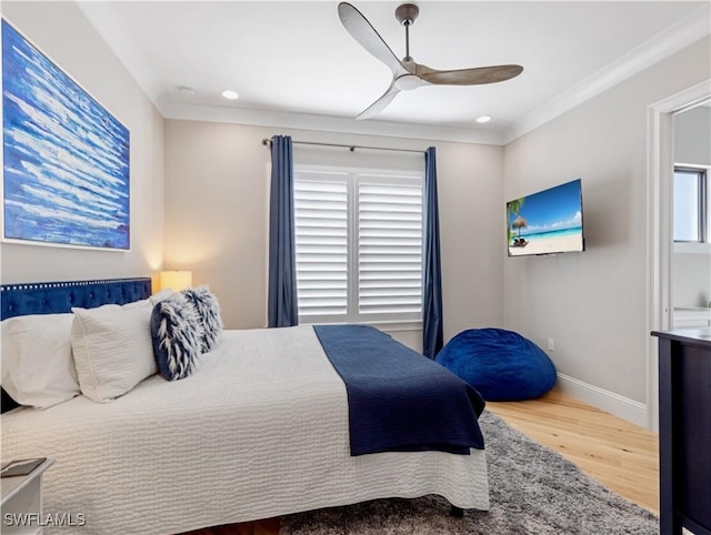 bedroom featuring ceiling fan, ornamental molding, multiple windows, and wood-type flooring