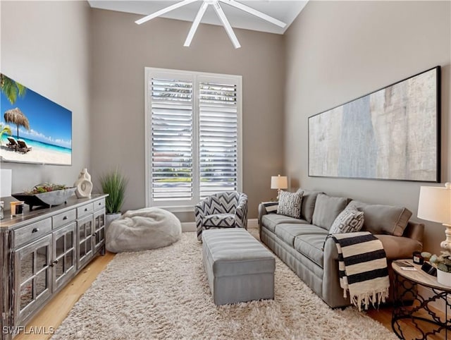 living room featuring lofted ceiling, light wood-type flooring, ceiling fan, and a healthy amount of sunlight