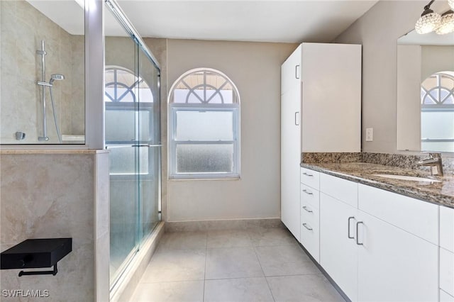 bathroom with walk in shower, vanity, and tile patterned flooring