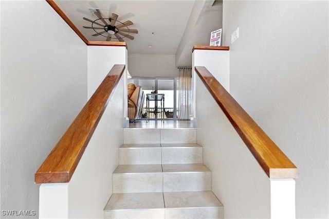 stairs featuring ceiling fan