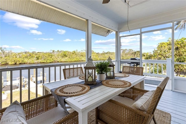 sunroom featuring ceiling fan and a water view