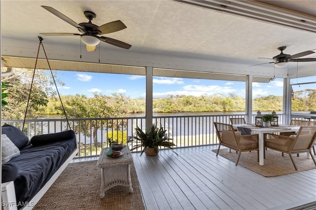 sunroom / solarium with ceiling fan and a water view