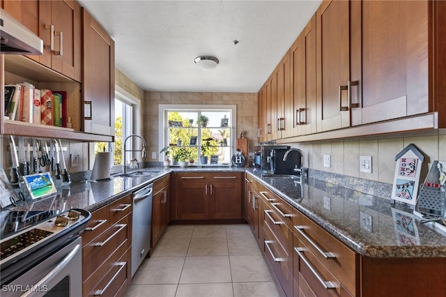 kitchen featuring range hood, sink, stainless steel appliances, light tile patterned floors, and dark stone counters