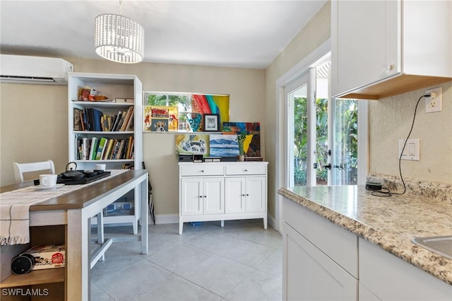 interior space with decorative light fixtures, white cabinetry, a wall unit AC, and an inviting chandelier