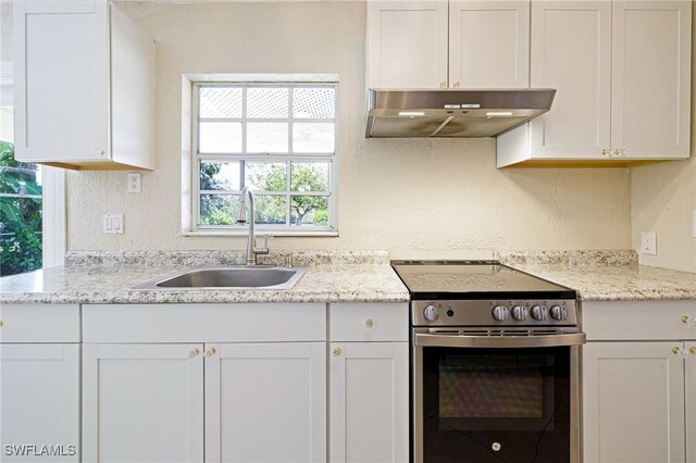 3968 Aloha Ln, Bonita Springs, FL 34134 - kitchen with stainless steel electric range, under cabinet range hood, white cabinets, and light stone counters