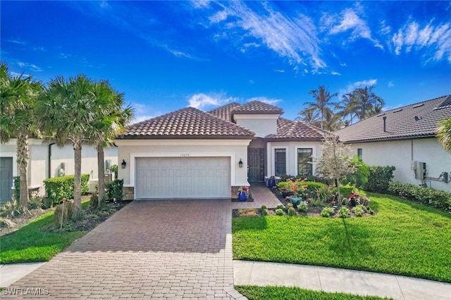 mediterranean / spanish-style home featuring stucco siding, a front lawn, a tile roof, decorative driveway, and an attached garage