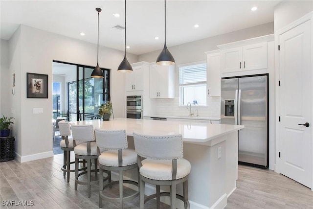 kitchen featuring stainless steel appliances, tasteful backsplash, a center island, and light wood finished floors