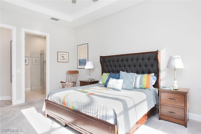 bedroom with visible vents, light carpet, a tray ceiling, baseboards, and ceiling fan