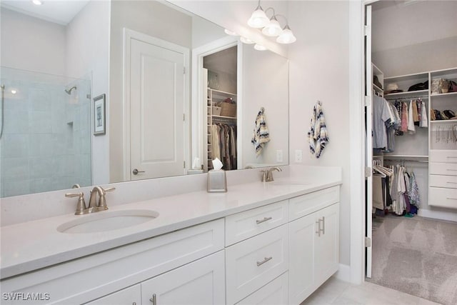 full bathroom with a sink, tiled shower, an inviting chandelier, and double vanity