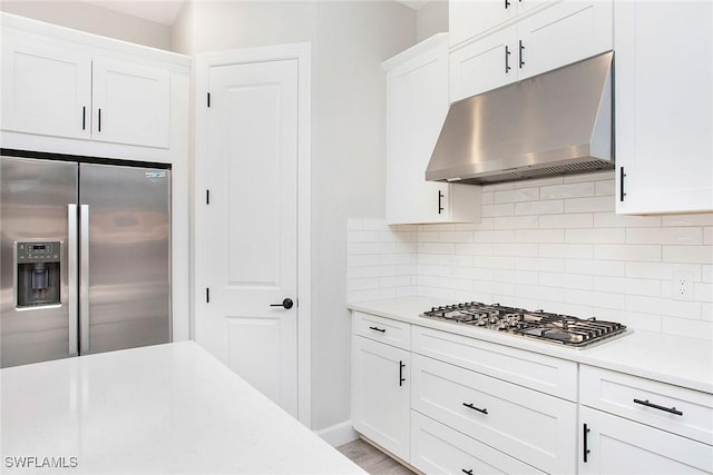 kitchen featuring stainless steel appliances, decorative backsplash, light countertops, under cabinet range hood, and white cabinetry