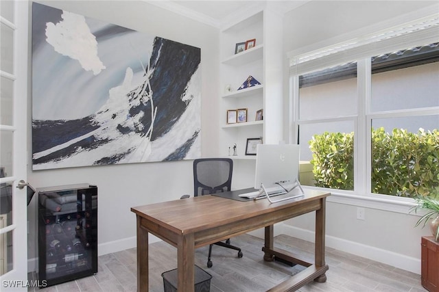 office area featuring built in features, light wood-style floors, baseboards, and ornamental molding