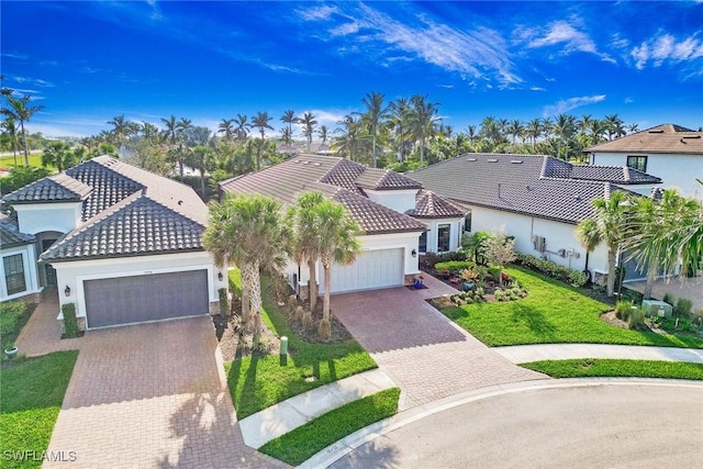 mediterranean / spanish-style home featuring a tiled roof, a front yard, stucco siding, decorative driveway, and a garage