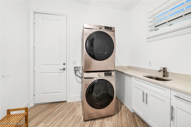 washroom with cabinets, stacked washing maching and dryer, crown molding, and sink