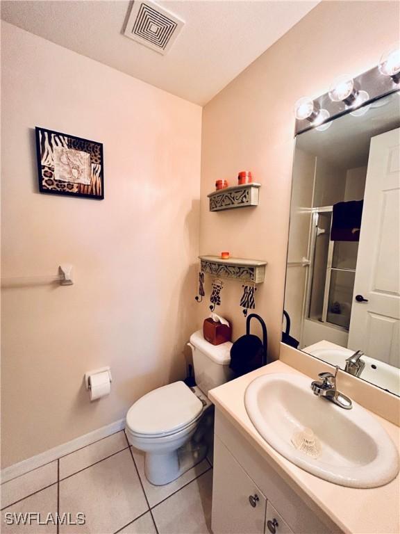 bathroom featuring tile patterned flooring, vanity, toilet, and a shower with door