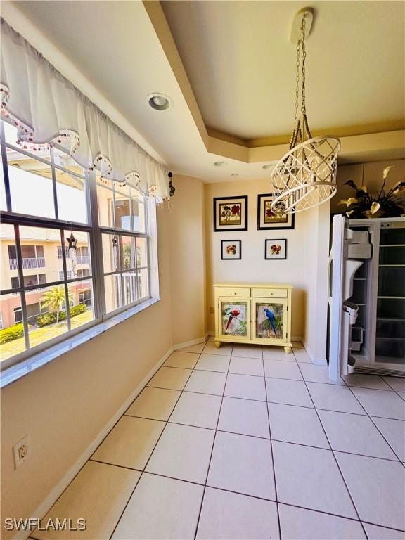 unfurnished dining area featuring tile patterned floors, a notable chandelier, and a raised ceiling