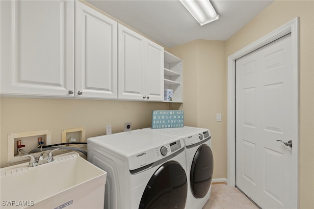 laundry room with washing machine and dryer, sink, light tile patterned floors, and cabinets