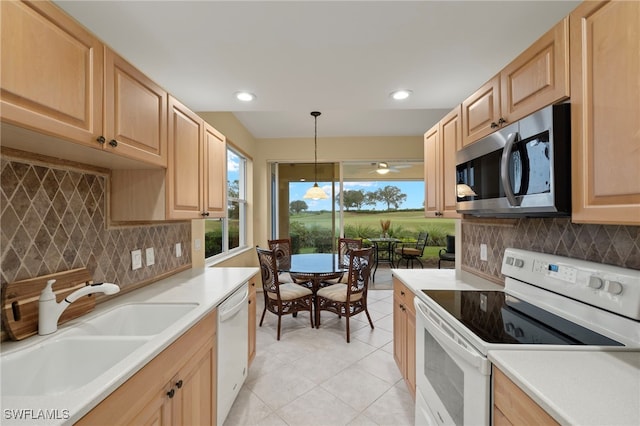 kitchen with light tile patterned flooring, light brown cabinetry, sink, decorative light fixtures, and white appliances