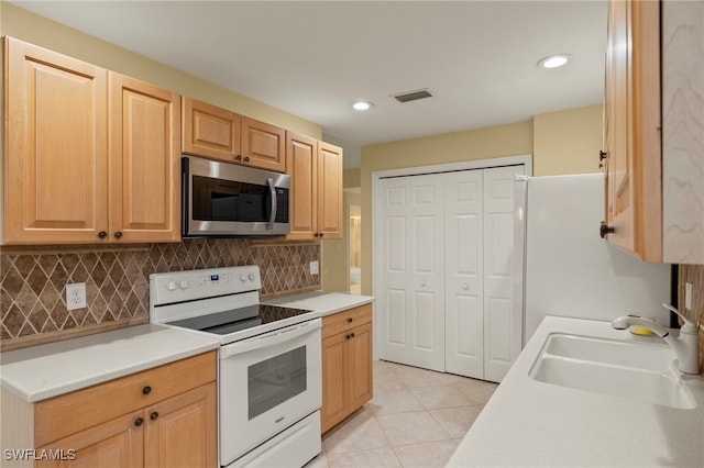 kitchen with white appliances, sink, light tile patterned floors, light brown cabinetry, and tasteful backsplash