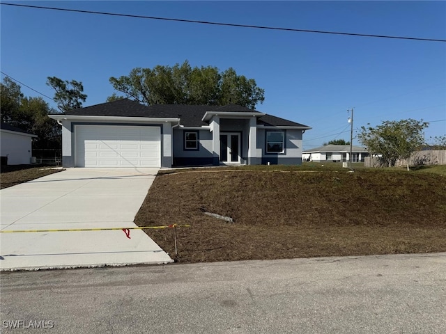 view of front of home with stucco siding, driveway, french doors, and a garage