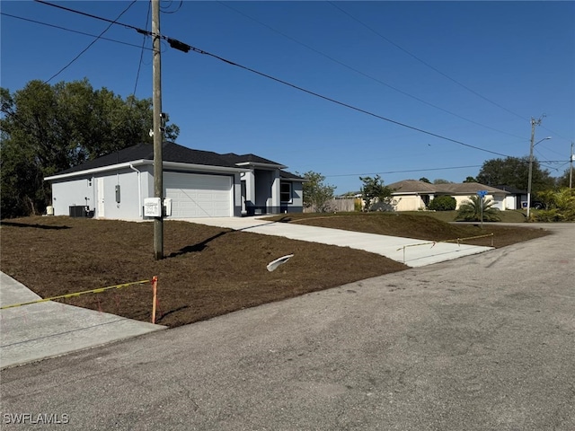 view of front facade with a garage, central AC, and driveway