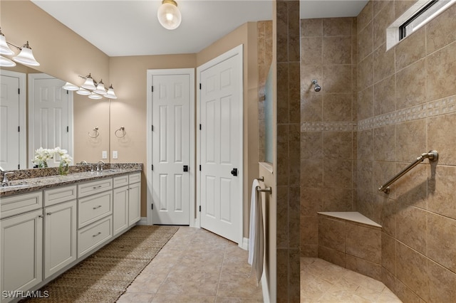 bathroom with a tile shower and vanity