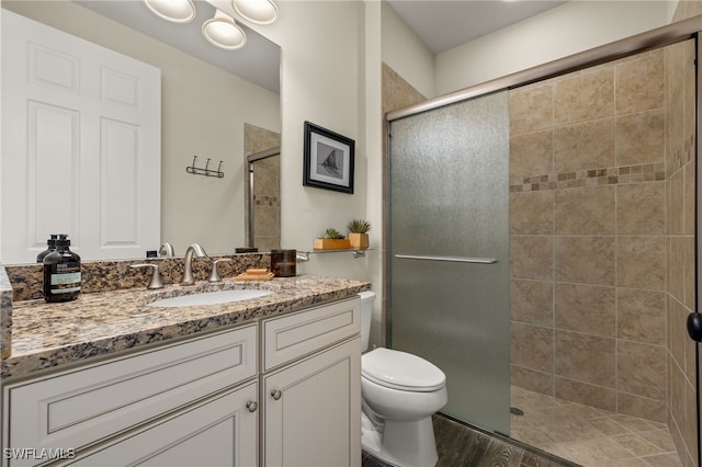 bathroom featuring hardwood / wood-style floors, vanity, toilet, and a shower with door