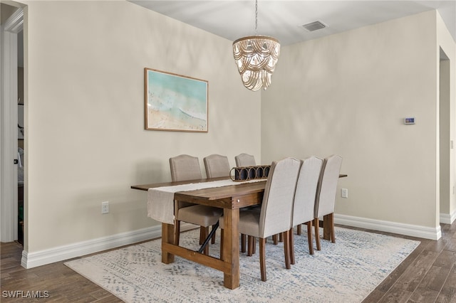 dining space with dark hardwood / wood-style floors and a notable chandelier