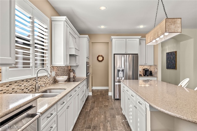 kitchen with pendant lighting, white cabinets, sink, light stone countertops, and stainless steel appliances