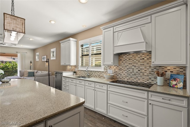 kitchen with backsplash, light stone counters, custom range hood, black electric cooktop, and sink