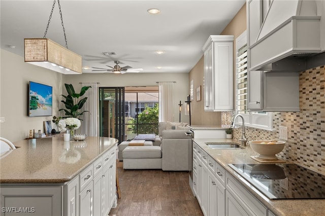 kitchen with backsplash, white cabinetry, hanging light fixtures, and sink