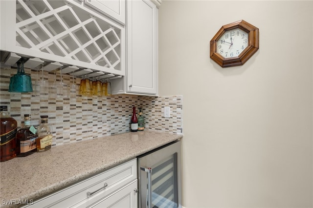 bar featuring backsplash, white cabinetry, wine cooler, and light stone counters