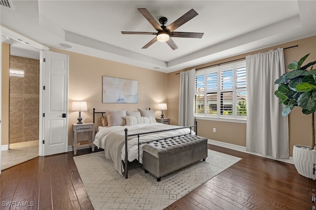 bedroom featuring a raised ceiling, ceiling fan, and dark wood-type flooring