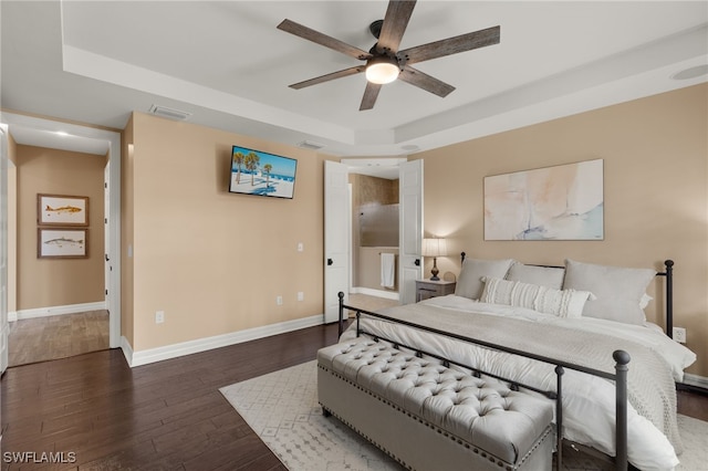 bedroom with a tray ceiling, ceiling fan, and dark hardwood / wood-style floors