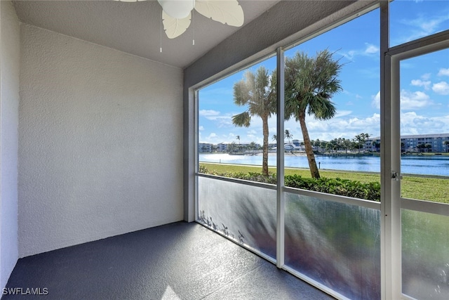 unfurnished sunroom featuring ceiling fan and a water view