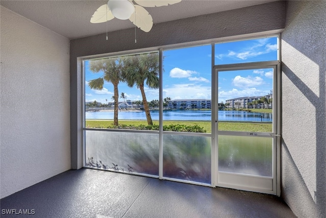 unfurnished sunroom with a water view, ceiling fan, and a healthy amount of sunlight