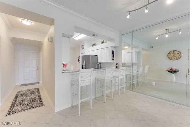 16635 Lake Circle Dr Unit 614, Fort Myers, FL 33908 - kitchen with stainless steel fridge, a kitchen bar, ornamental molding, white cabinets, and a peninsula