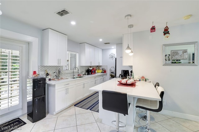 kitchen featuring tasteful backsplash, white cabinetry, sink, and decorative light fixtures