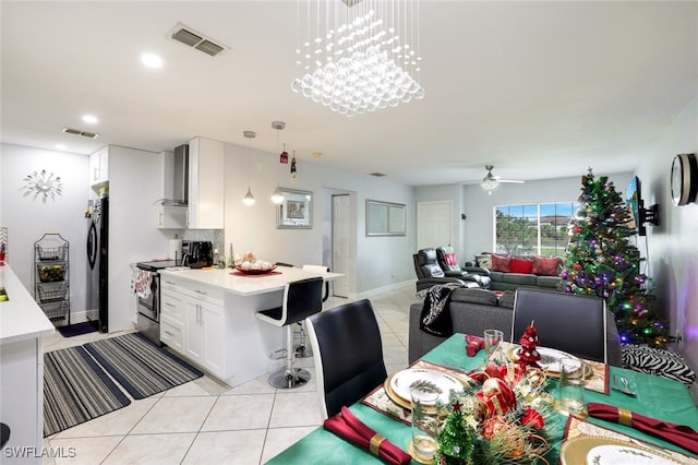 interior space with black fridge, pendant lighting, electric stove, a breakfast bar, and white cabinets