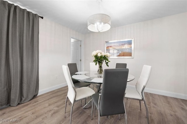 dining space featuring light hardwood / wood-style floors and a notable chandelier