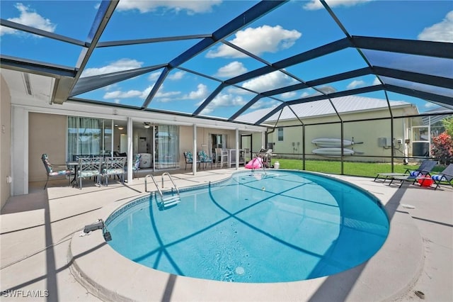 view of swimming pool with glass enclosure, ceiling fan, and a patio