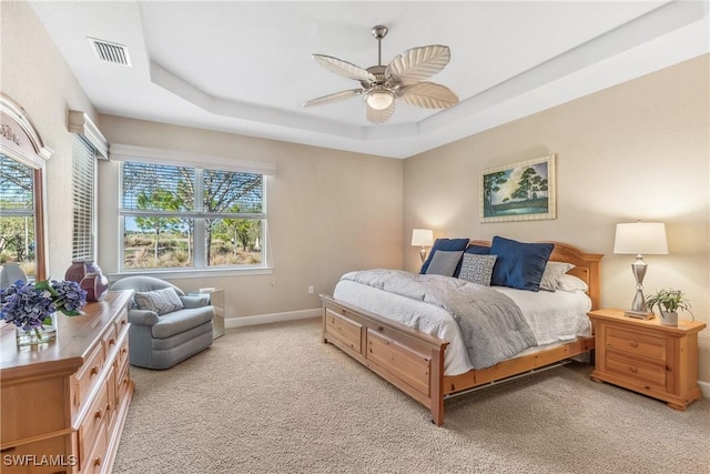 bedroom with a tray ceiling, ceiling fan, and light colored carpet