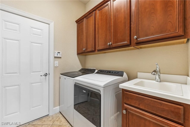 clothes washing area featuring washer and clothes dryer, light tile patterned floors, cabinets, and sink