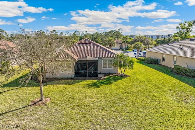 back of property with a lawn and a lanai