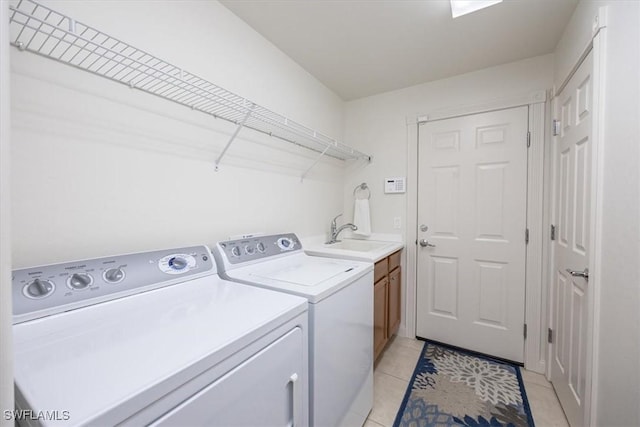 laundry area with cabinets, independent washer and dryer, light tile patterned floors, and sink