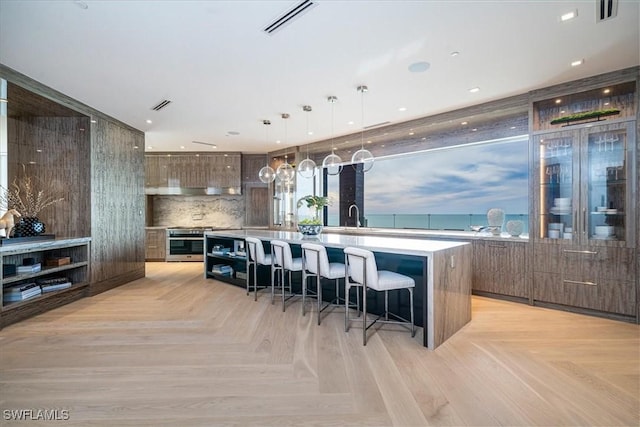 kitchen featuring backsplash, a center island, light parquet floors, hanging light fixtures, and a kitchen breakfast bar