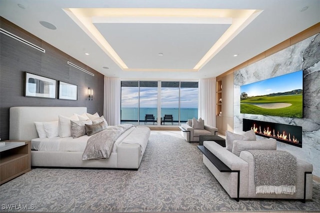 living room with a premium fireplace, a raised ceiling, and expansive windows