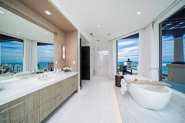 bathroom with a tub, a wall of windows, a water view, and vanity